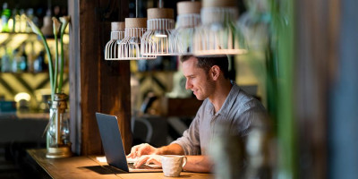 Homme qui travaille sur son ordinateur dans un café ou espace coworking